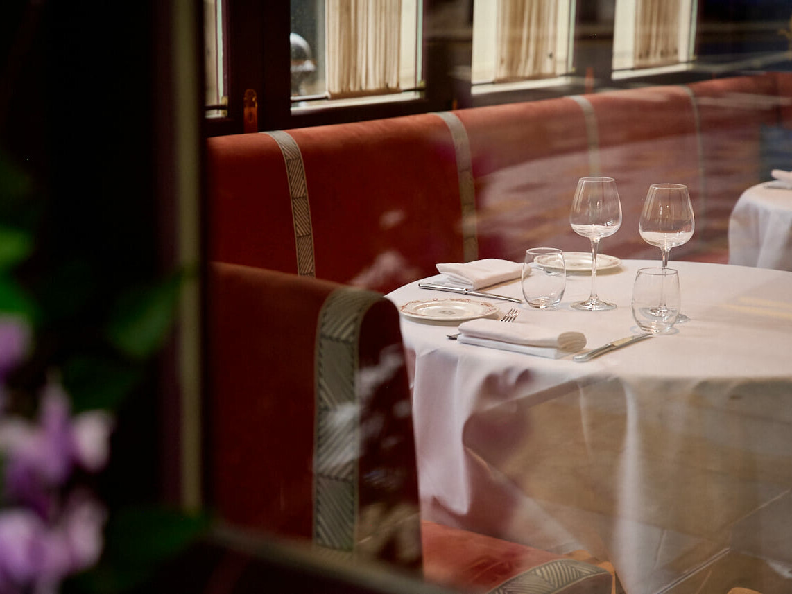 Table set beside a red velvet banquette in the dining room of a Tuscan restaurant in London